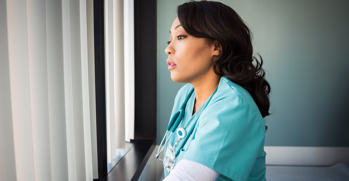 nurse looks sadly out window