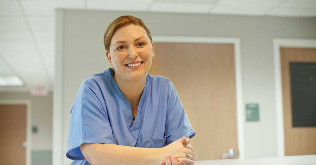 nurse smiles and leans on desk