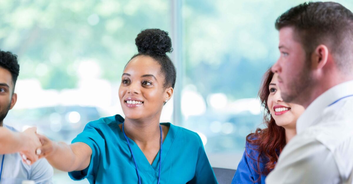 Nurse shakes hands with another person in a group of other medical professionals