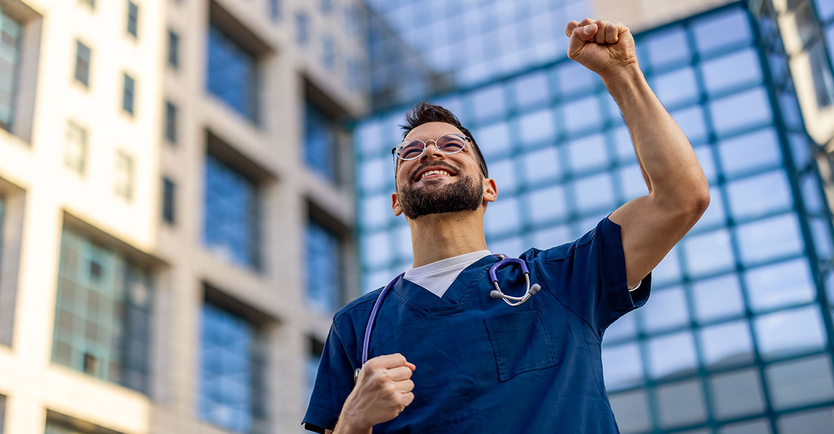 Excited male nurse standing outside healthcare facility