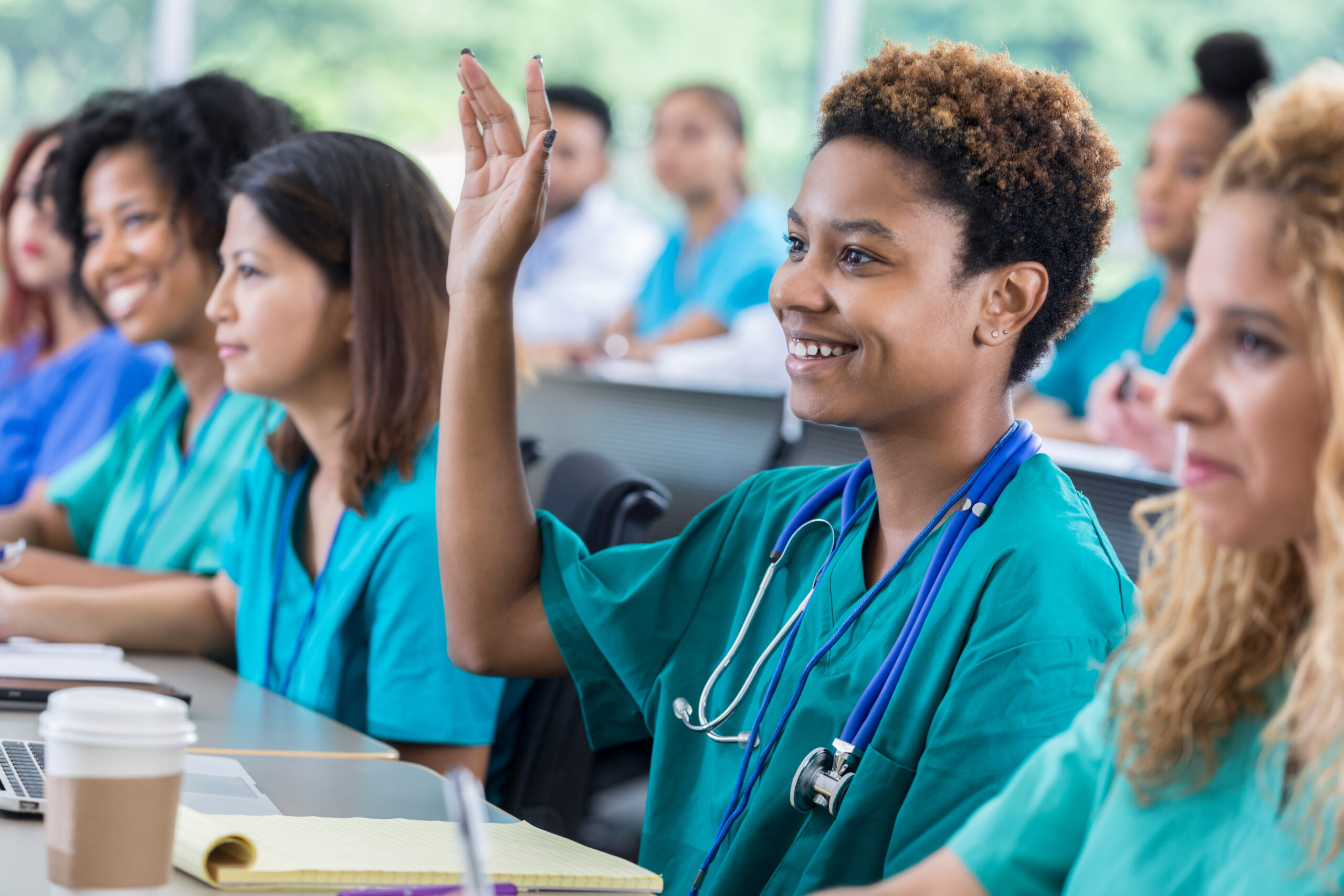 Smiling African American nursing student raises hand during class